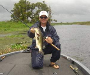 Man holding a Largemouth Bass up next to his fishing pole